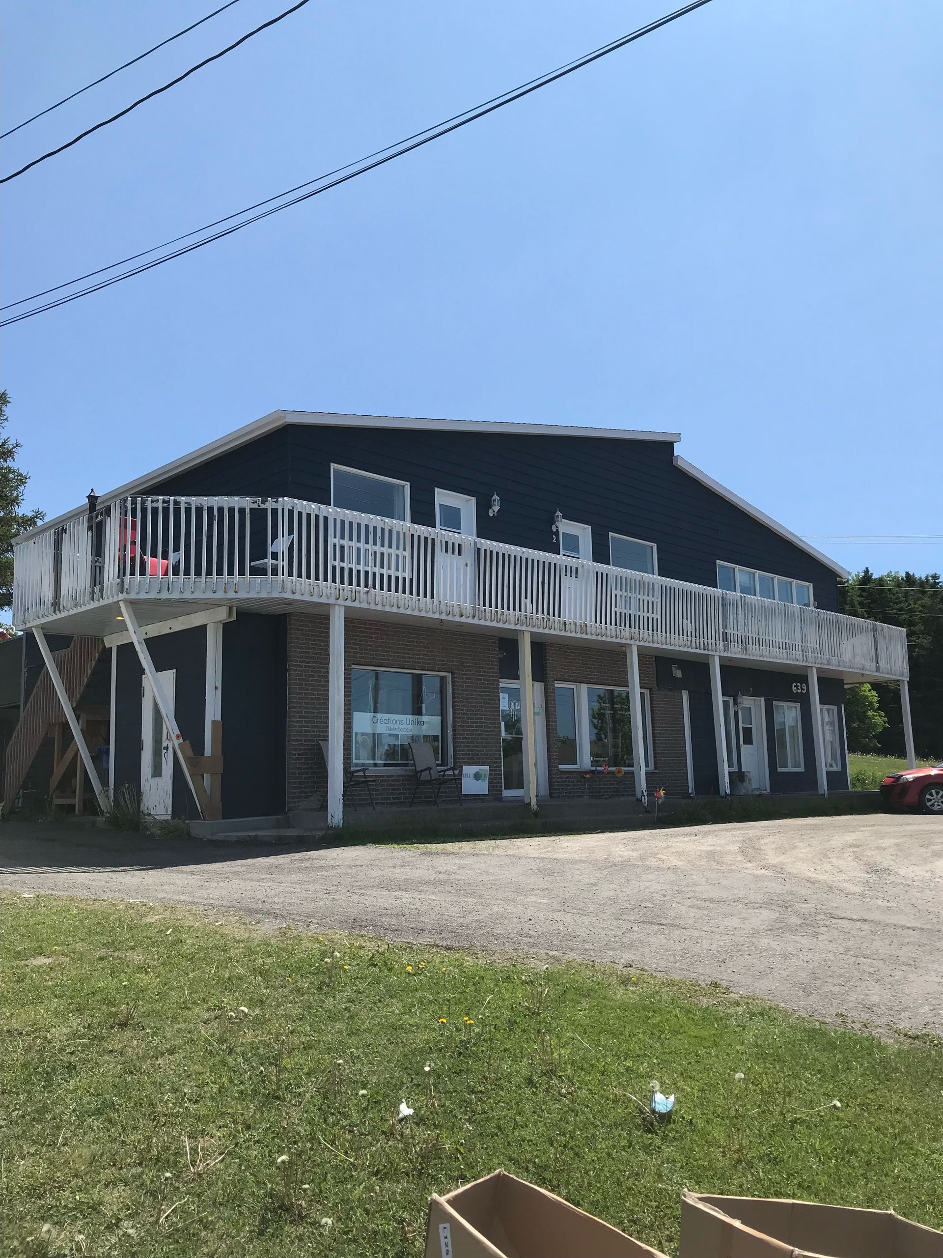 Une grande maison avec un balcon et une voiture garée devant.