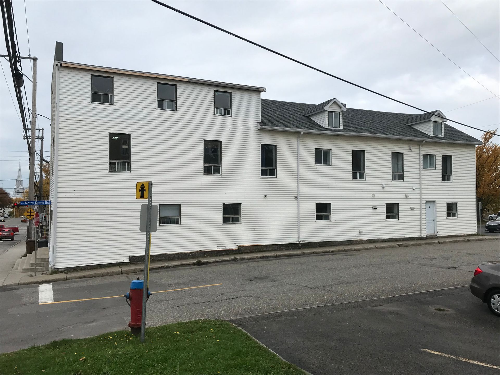 Un bâtiment blanc avec une bouche d'incendie devant lui