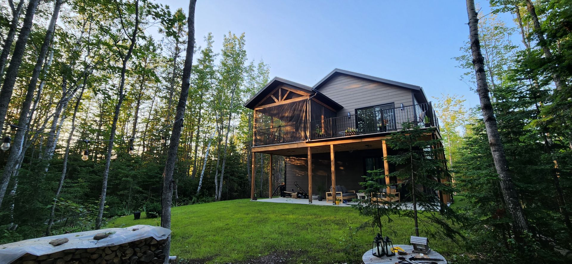 Une grande maison est située au sommet d'une colline verdoyante au milieu d'une forêt.