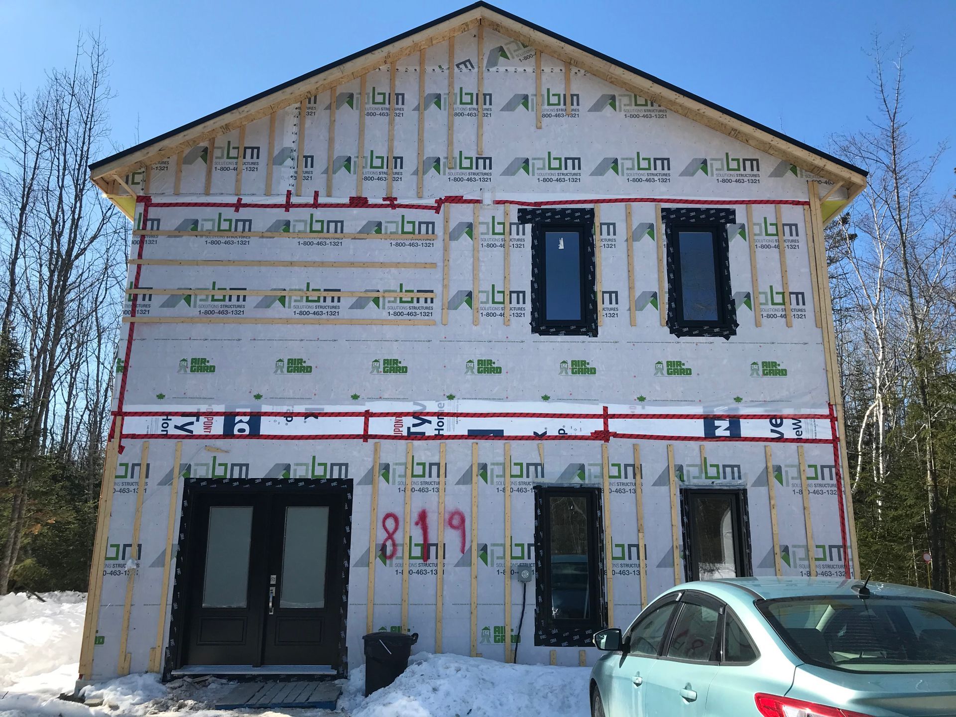 Une voiture est garée devant une maison en construction.
