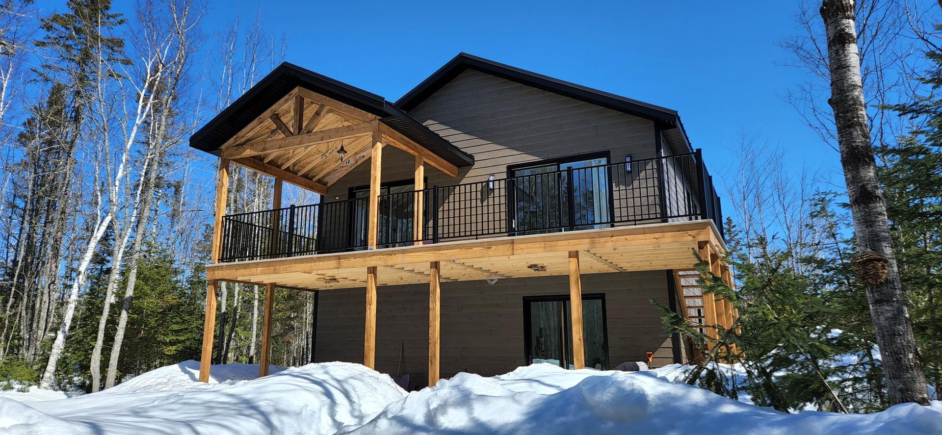 Une maison avec une grande terrasse au milieu d'une forêt enneigée.