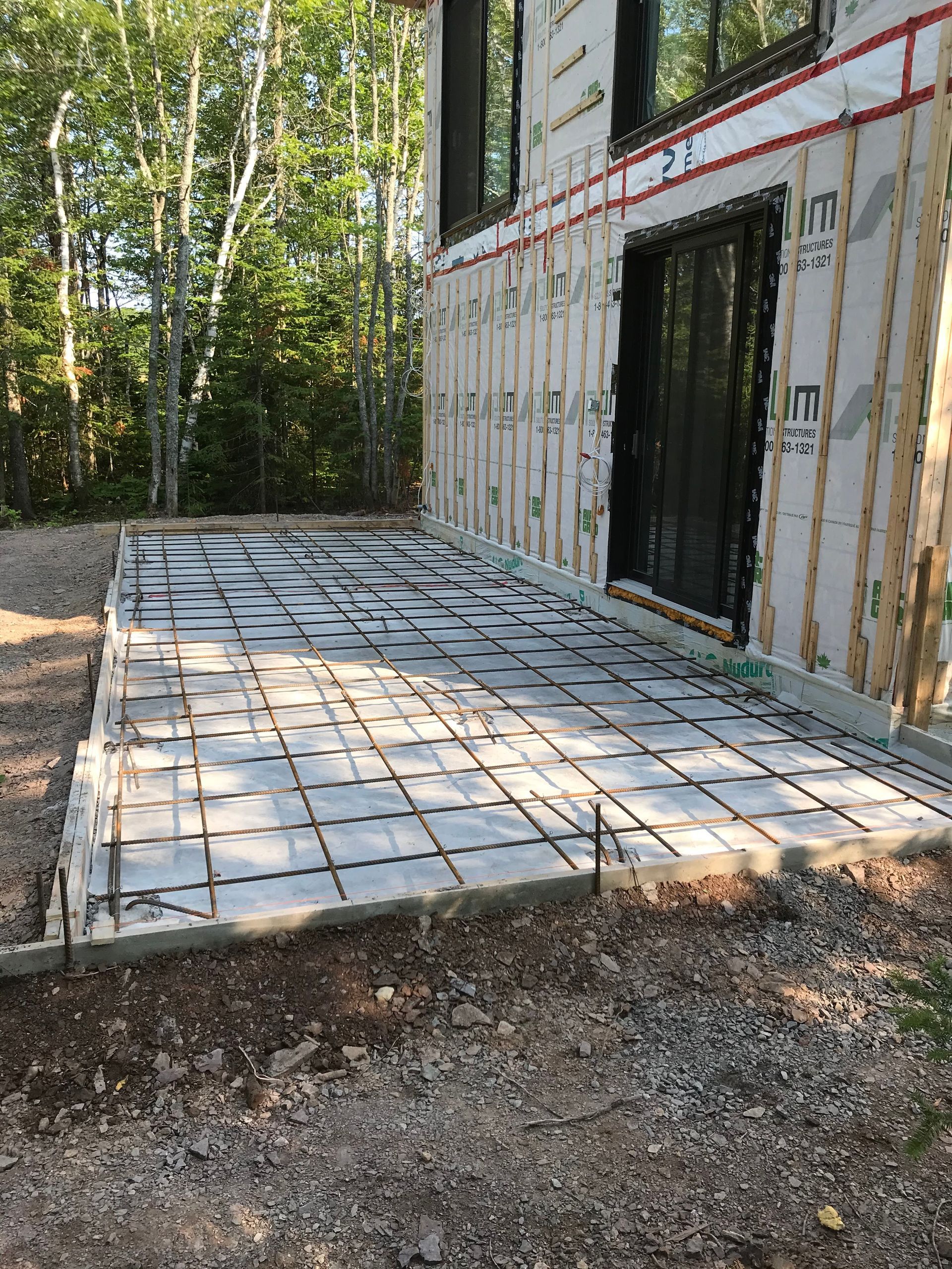 Un patio en béton est en cours de construction devant une maison.