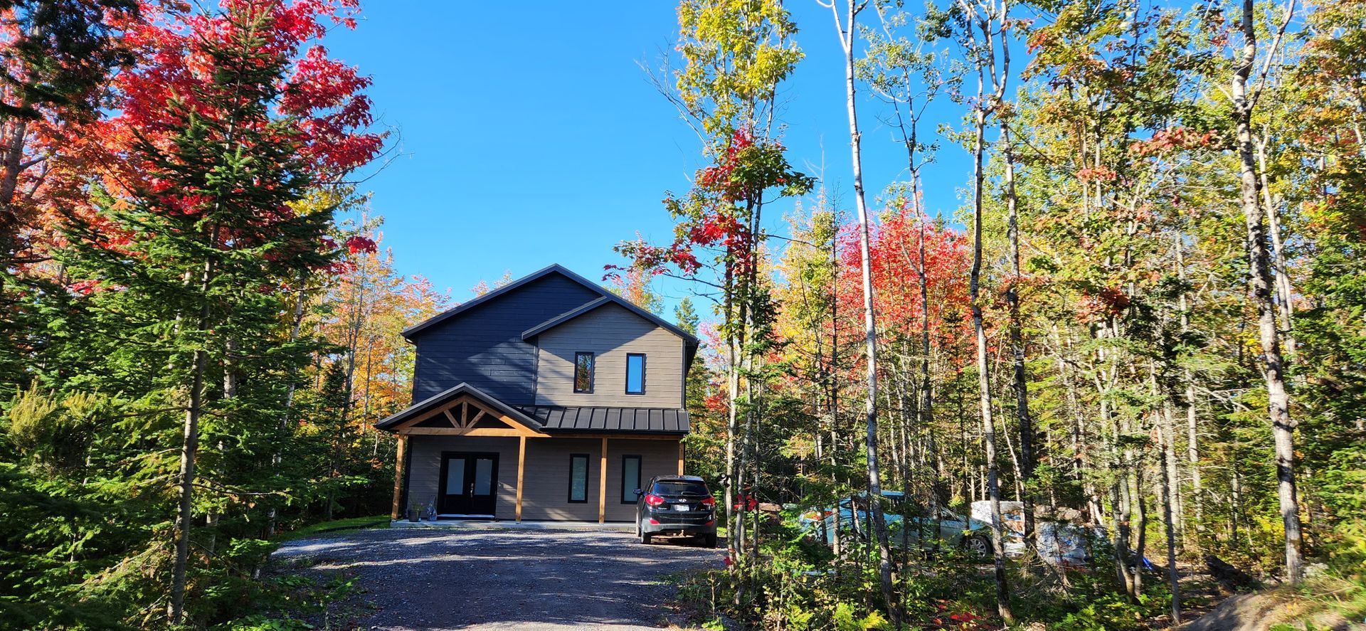 Une maison est entourée d'arbres et une voiture est garée devant elle.