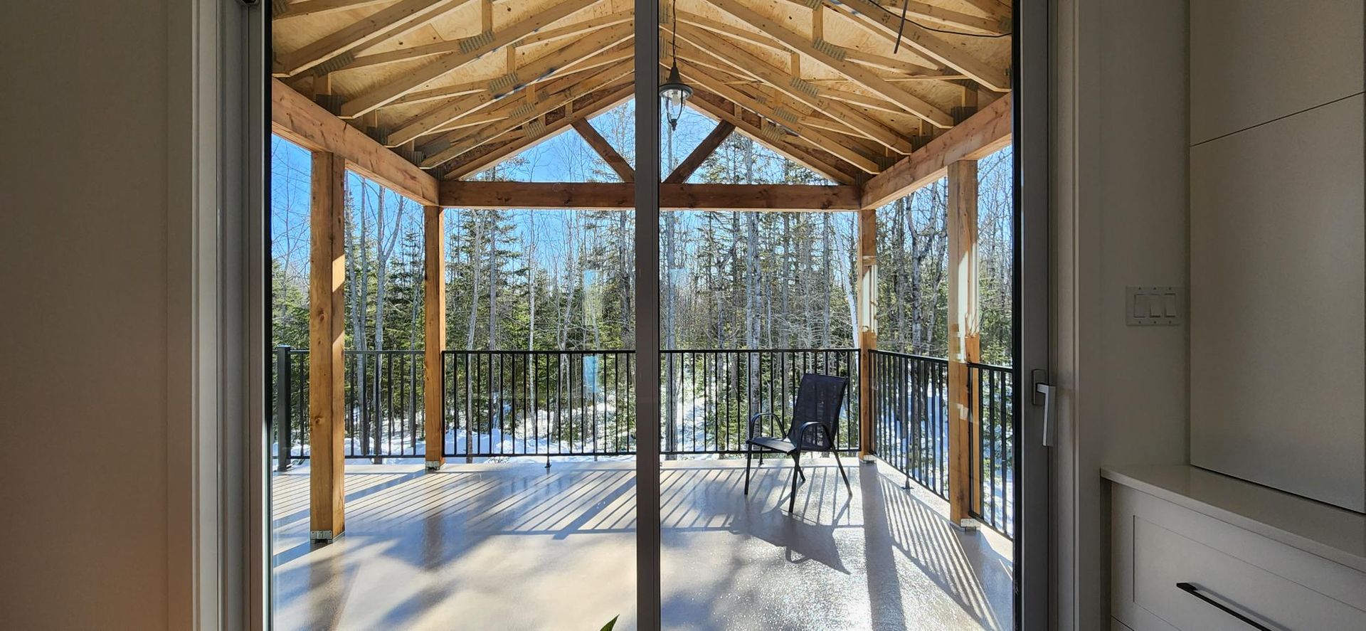 Une porte coulissante en verre donnant sur un balcon avec un toit en bois.