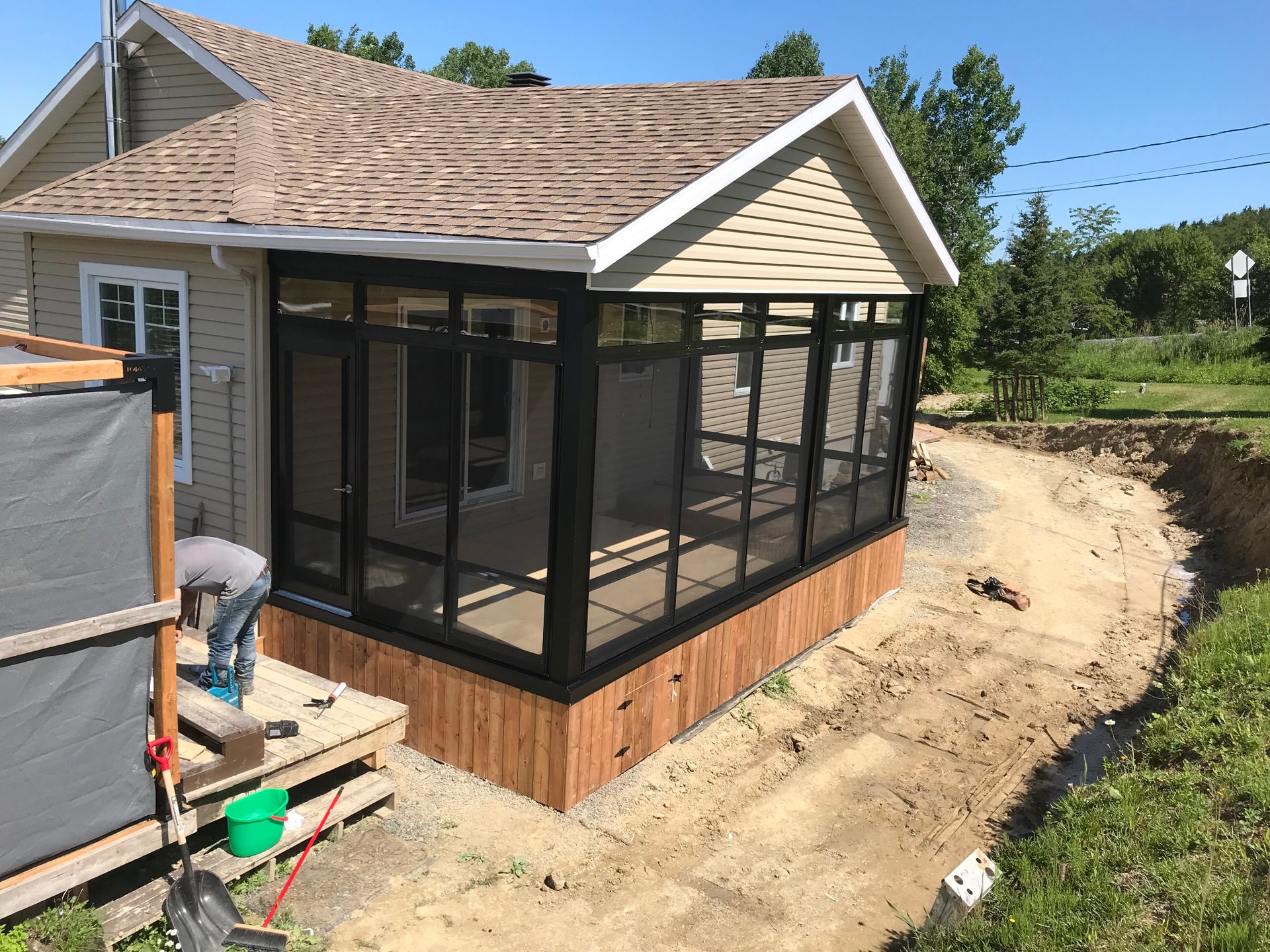 Un porche grillagé est en cours de construction sur le côté d'une maison.