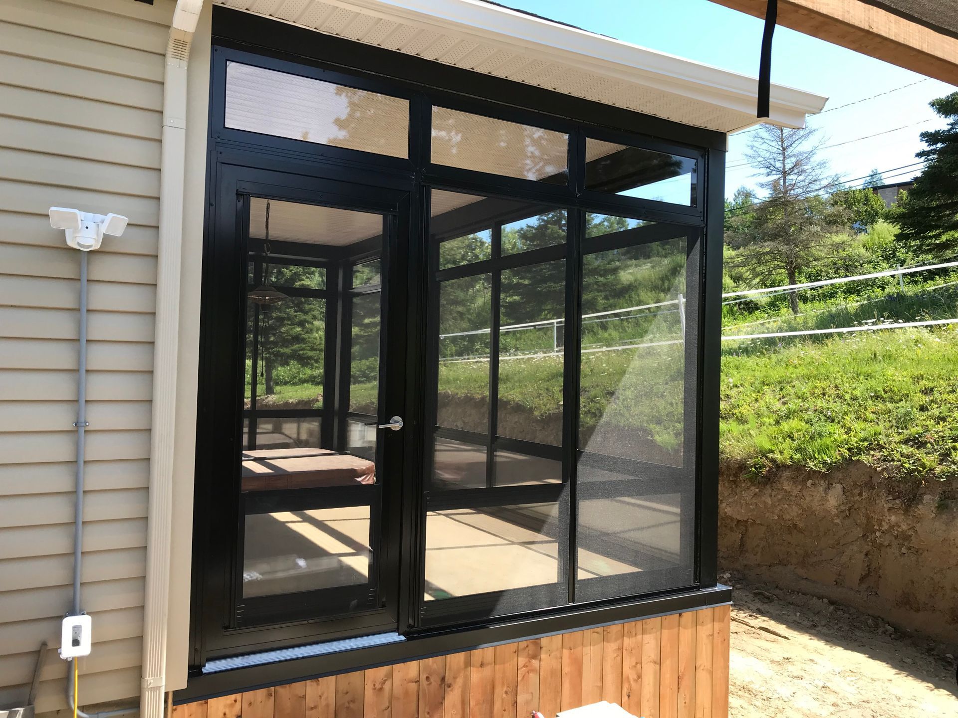 Un porche grillagé avec beaucoup de fenêtres sur le côté d'une maison.