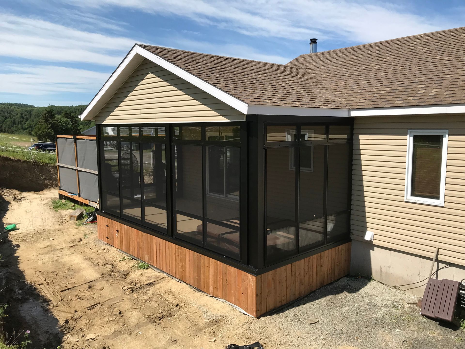 Un porche grillagé est en cours de construction sur le côté d'une maison.