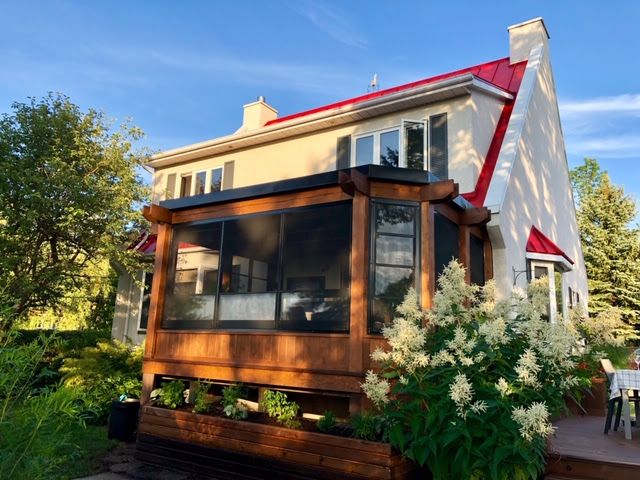 Une maison avec un porche grillagé et un toit rouge