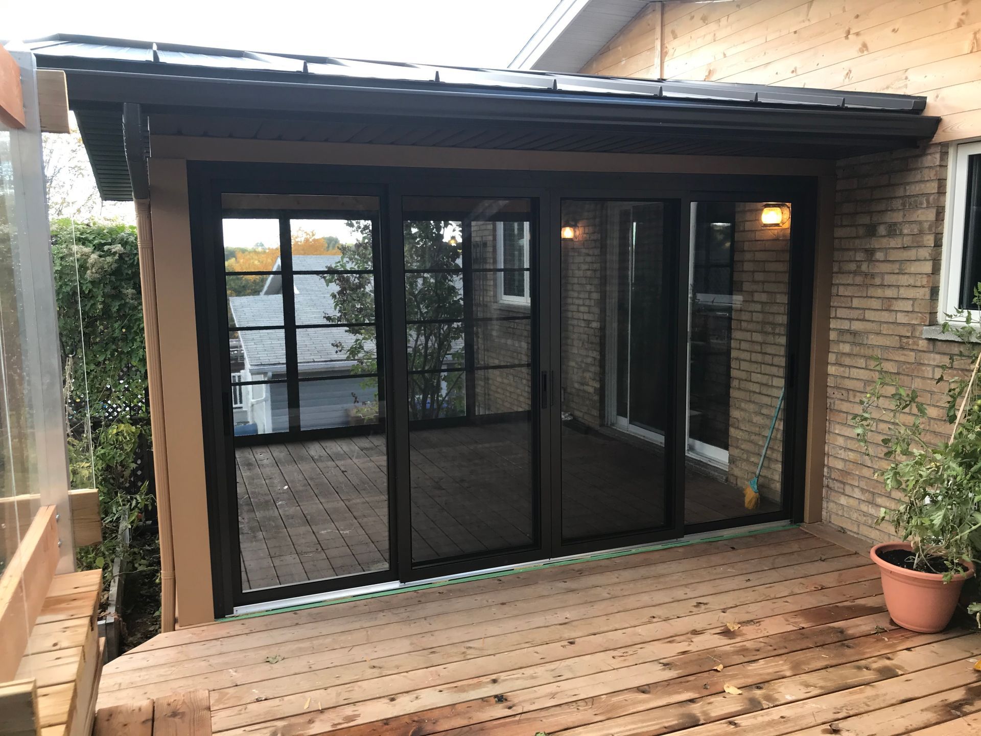 Une maison en briques avec des portes coulissantes en verre et une terrasse en bois.