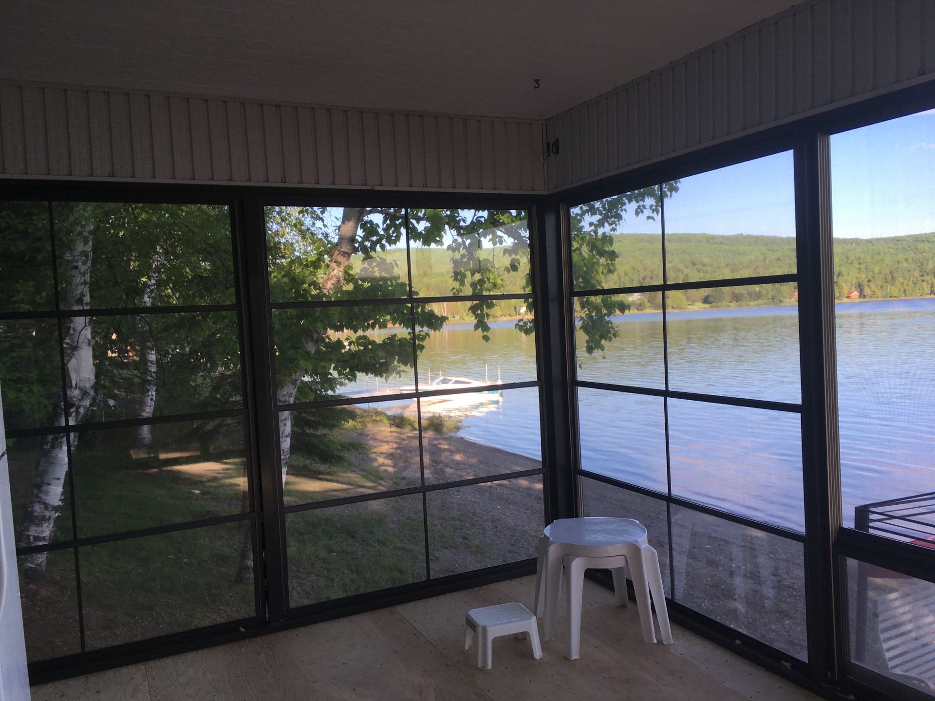 Une véranda grillagée avec vue sur un lac.