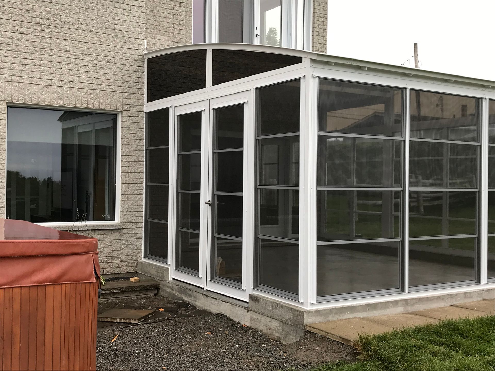 Un porche grillagé avec un bain à remous dans l'arrière-cour d'une maison.