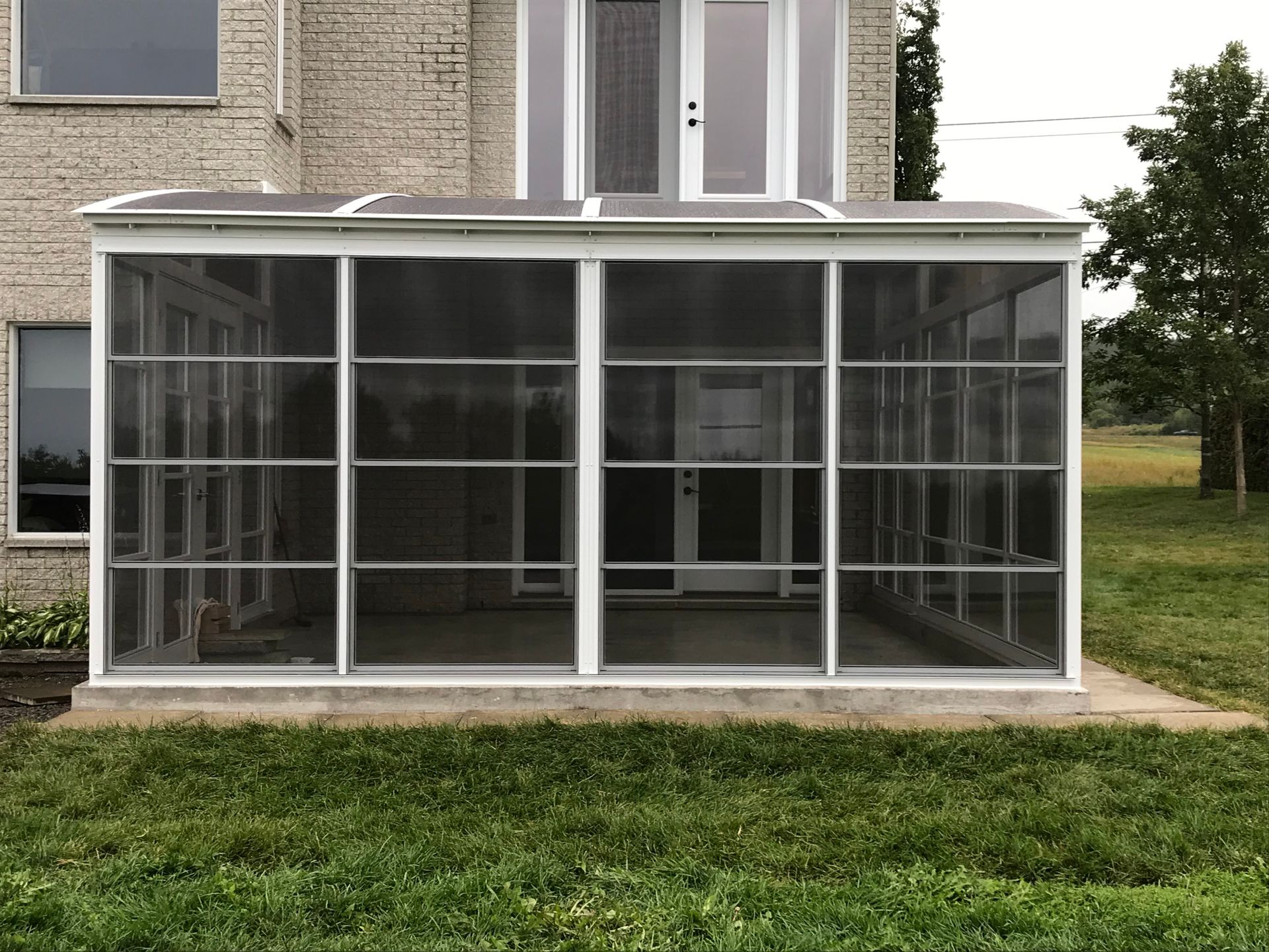 Un porche grillagé se trouve dans l'arrière-cour d'une maison.