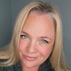 A woman with blonde hair and blue eyes is smiling for the camera.