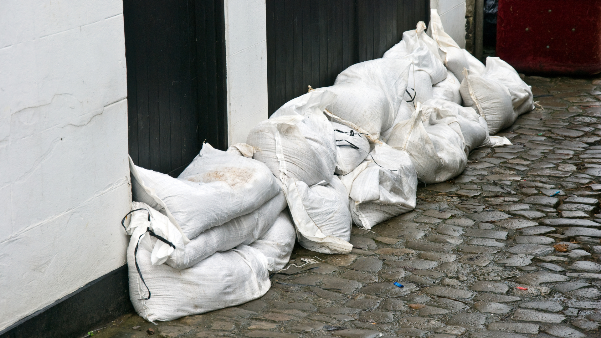 A row of sandbags on a cobblestone street next to a building.