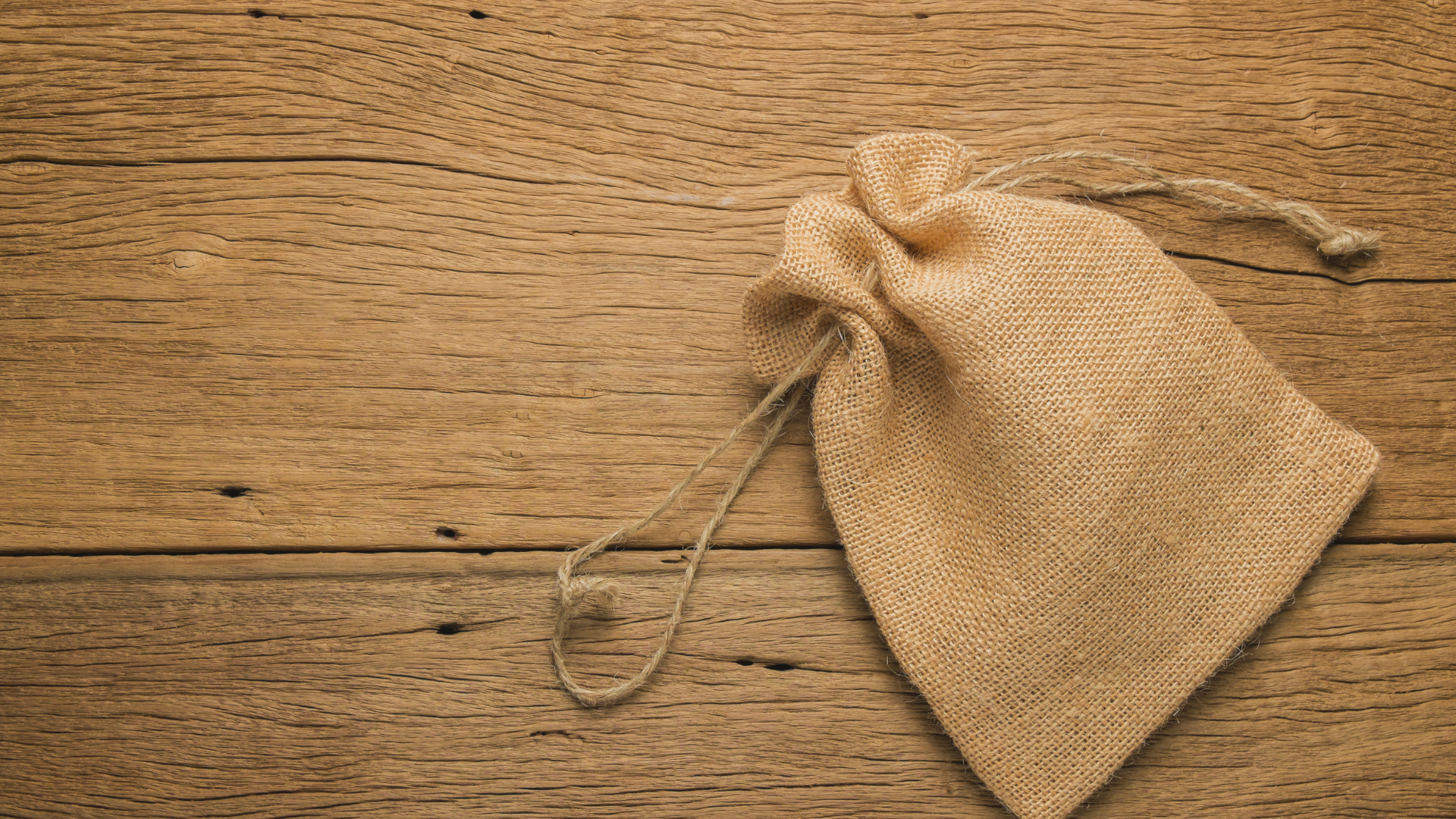 A small burlap bag is sitting on a wooden table.