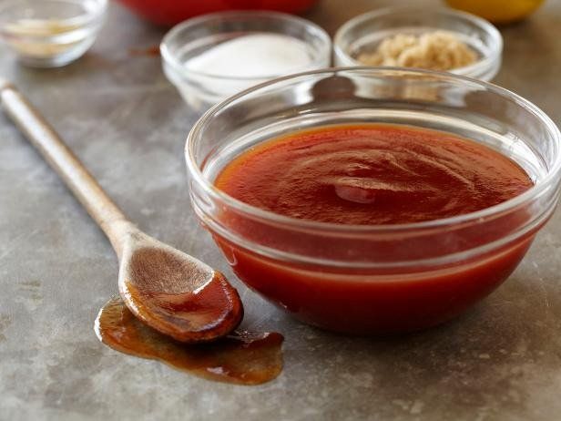 A bowl of tomato sauce next to a wooden spoon