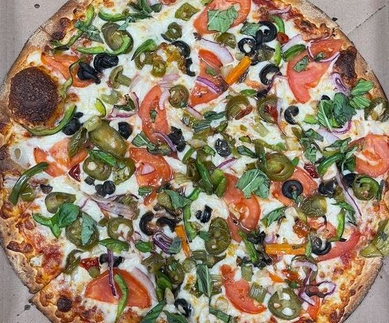 A pizza with pepperoni and cheese is sitting on a wooden cutting board.