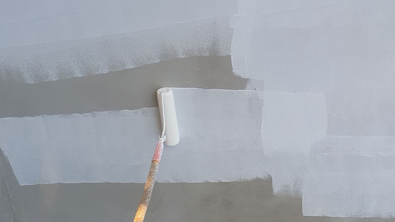 A man is painting a wall with a paint roller.