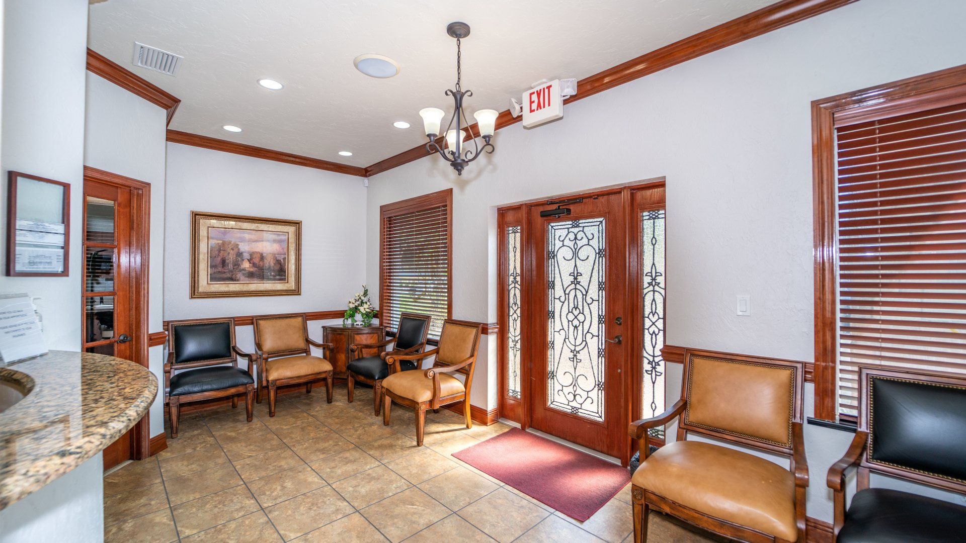 A waiting room with chairs and a fire exit sign.