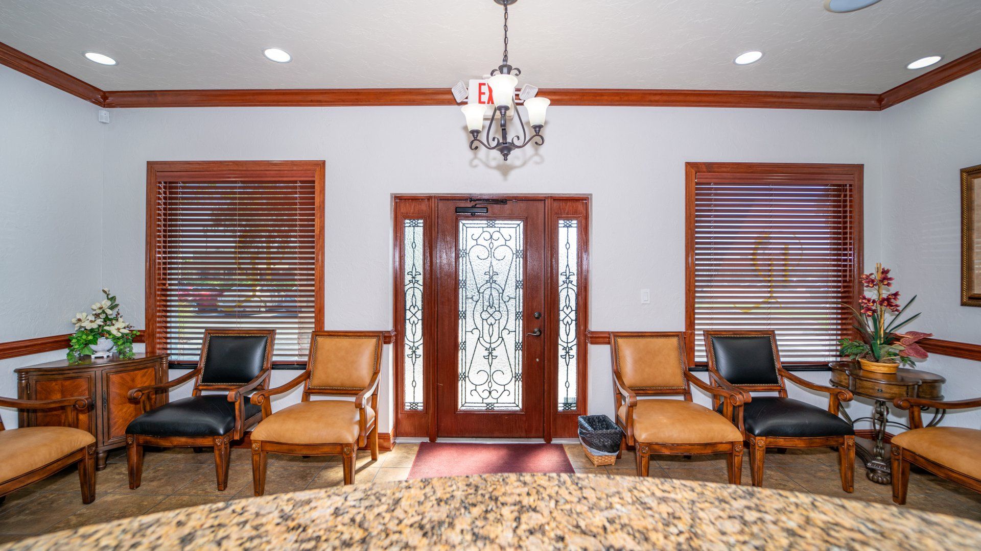 A waiting room with chairs , a table and a chandelier.