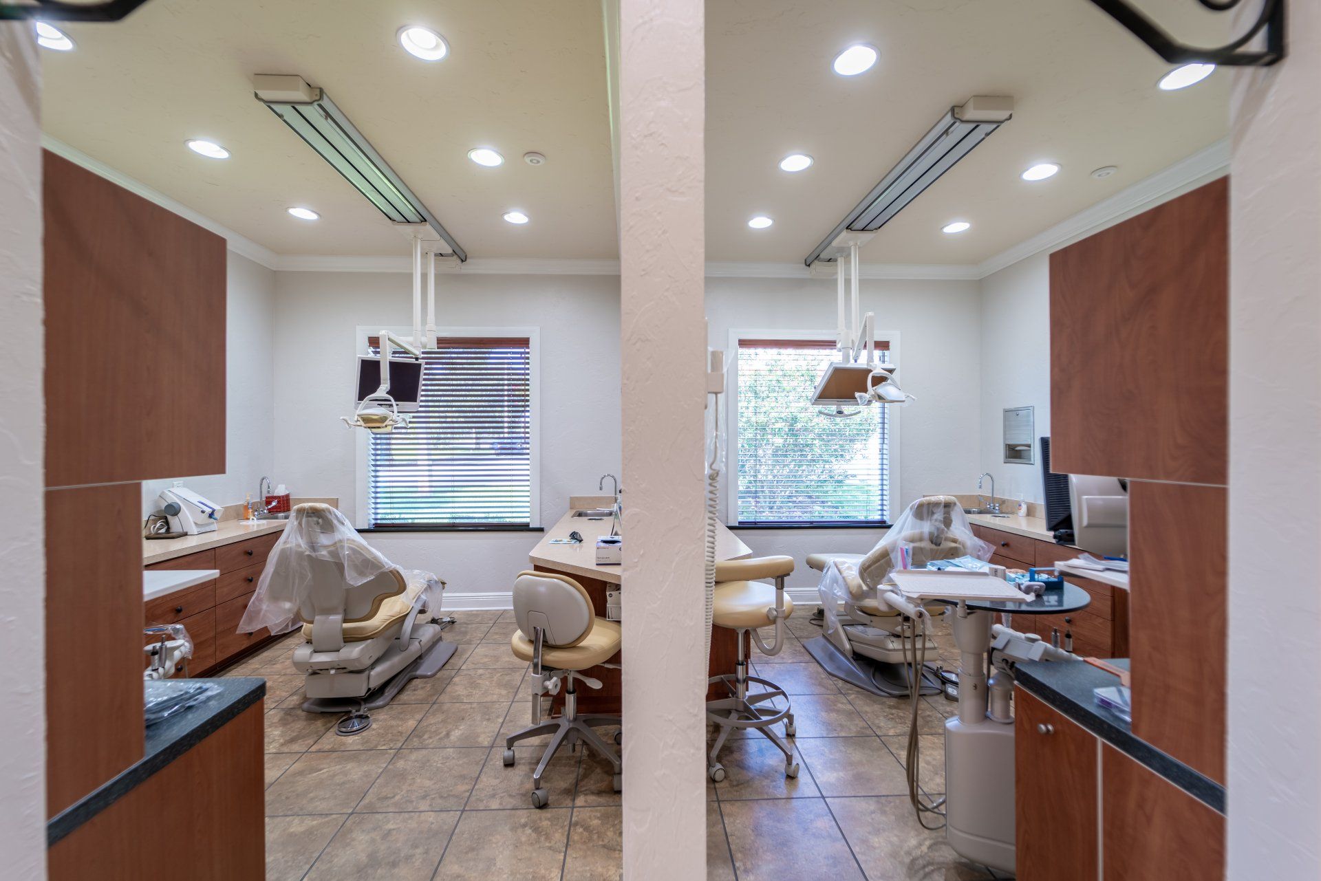 A dental office with two dental chairs and a window.