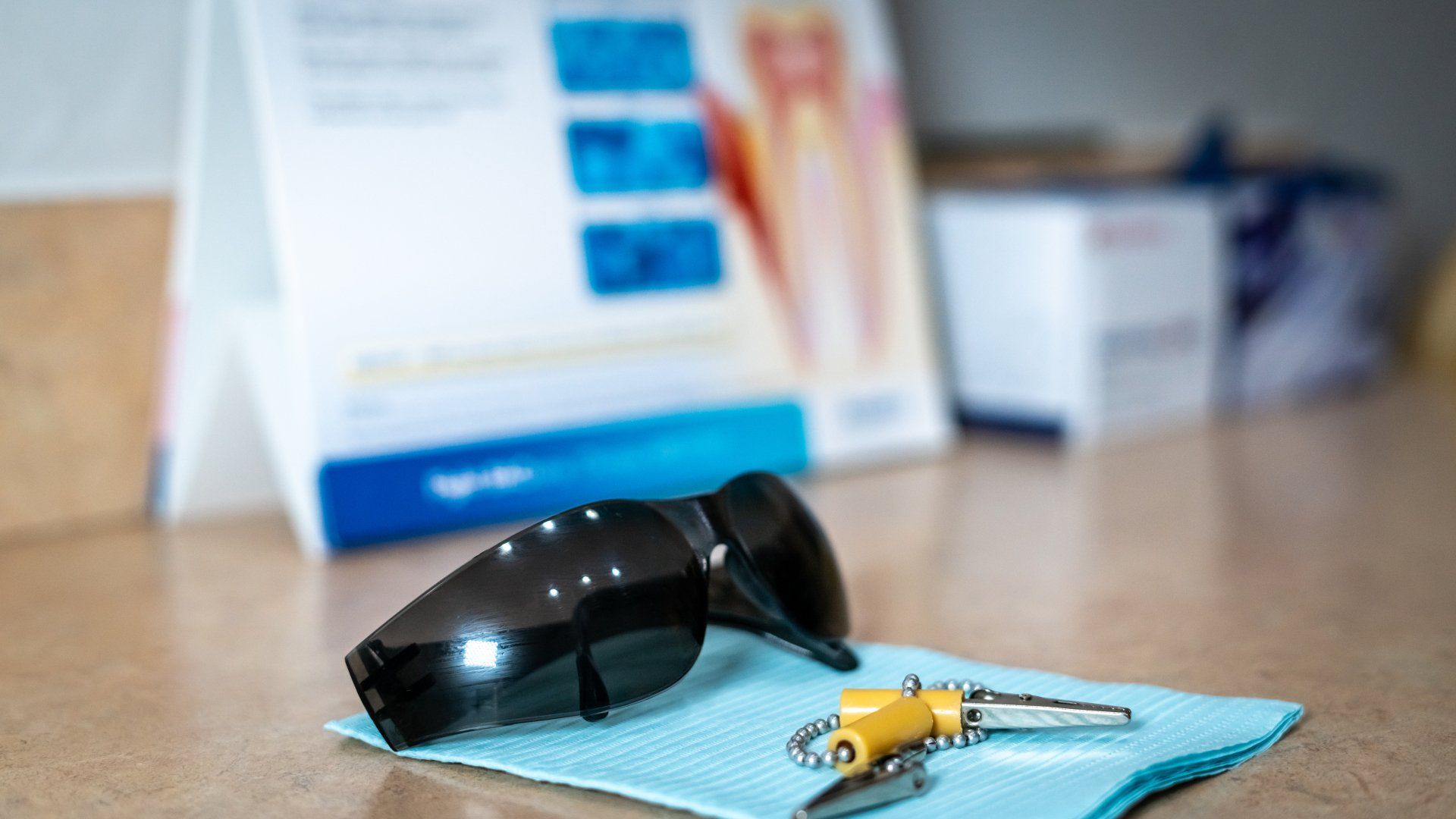 A pair of sunglasses and a pair of keys are on a table.