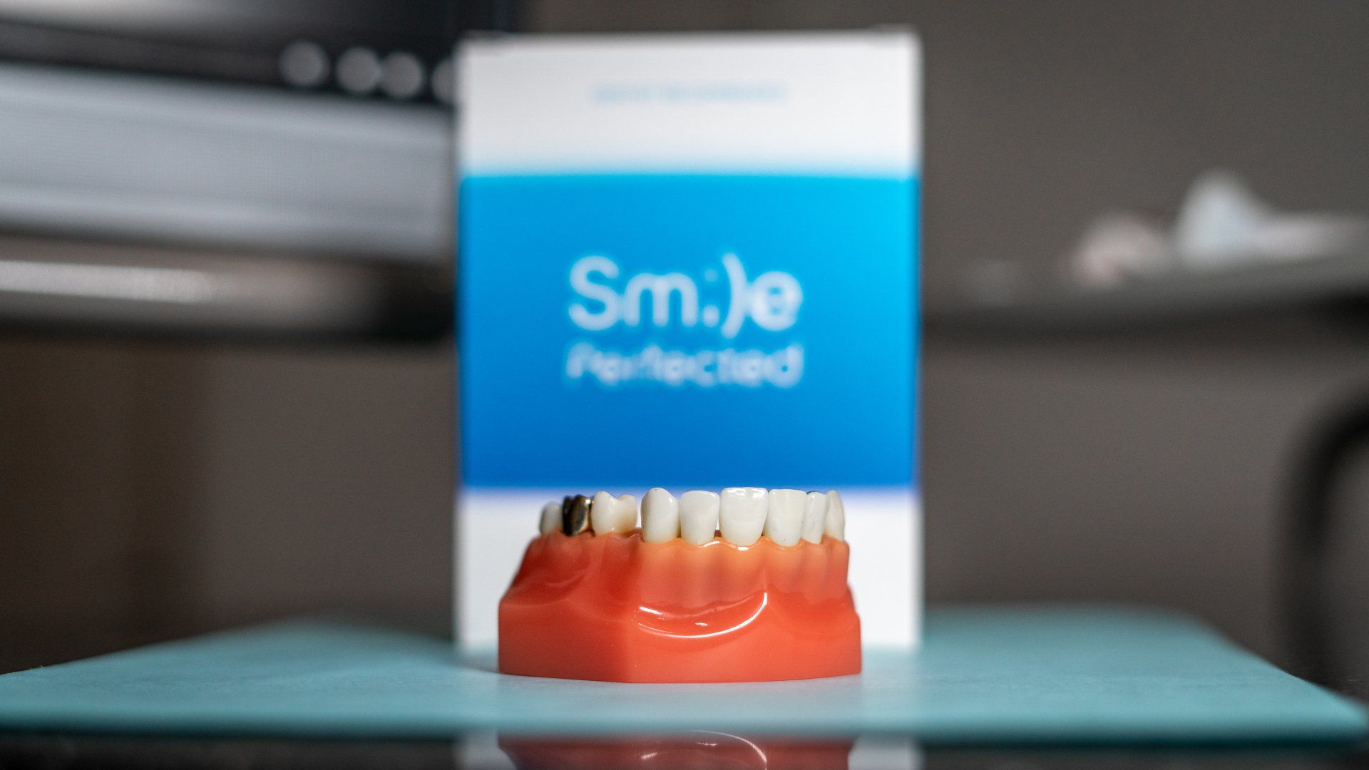 A model of teeth is sitting on a table next to a box that says smile perfected.