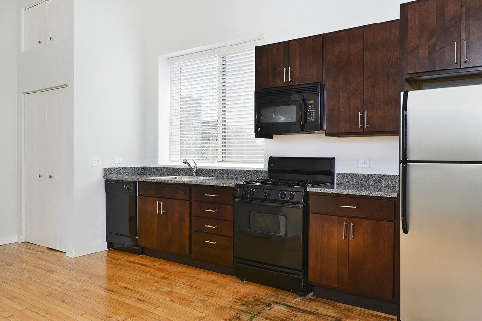 A kitchen with stainless steel appliances and wooden cabinets at 1471 N Milwaukee Apartments.