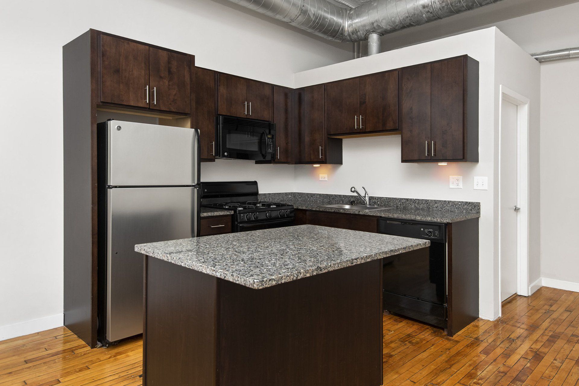 A kitchen with stainless steel appliances and granite counter tops at 1471 N Milwaukee Apartments.