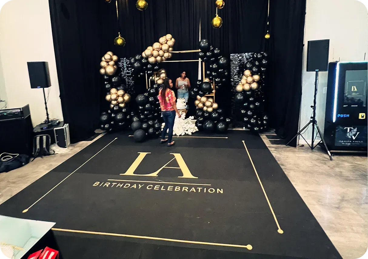Black and gold themed birthday party stage with balloons and a dance floor that reads 