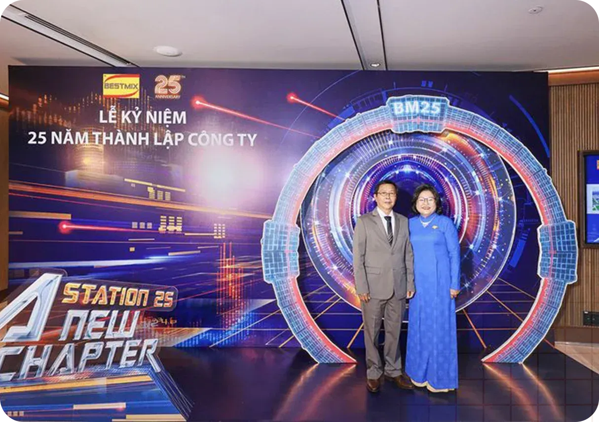 Two people standing in front of a backdrop celebrating a company's 25th anniversary.