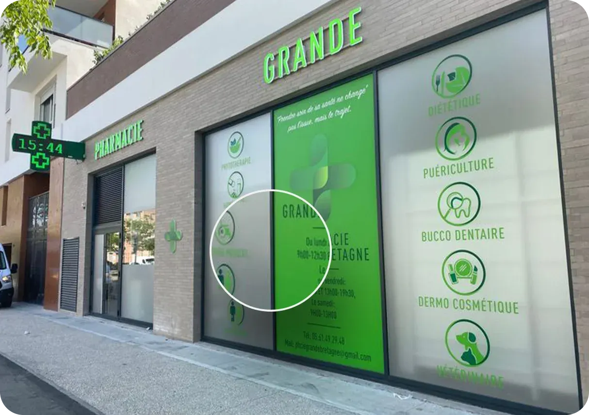 Pharmacy facade with large green signage, window displays, and a pharmacy cross.