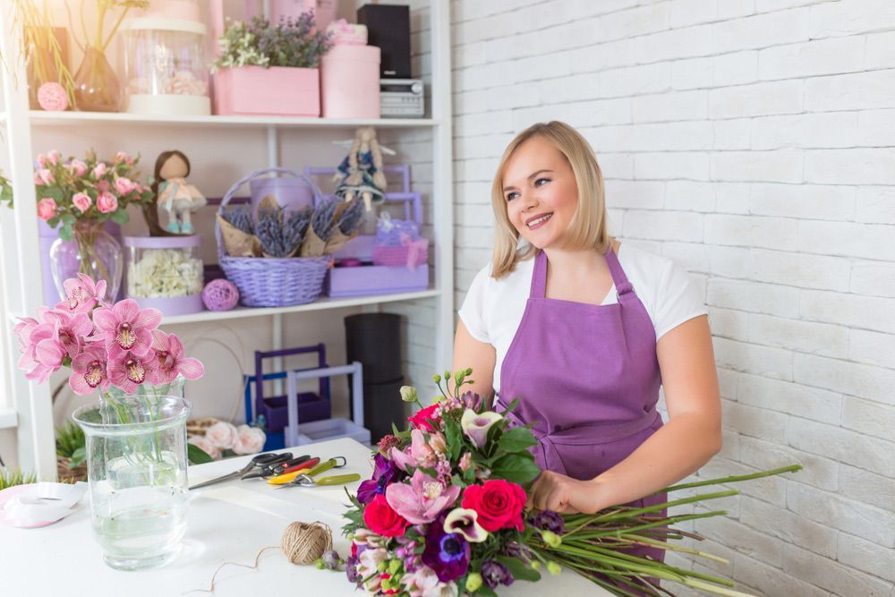 A Woman in A Purple Apron Is Making a Bouquet of Flowers in A Flower Shop — Pick-A-Bunch Florists & Gifts In Koumala, QLD
