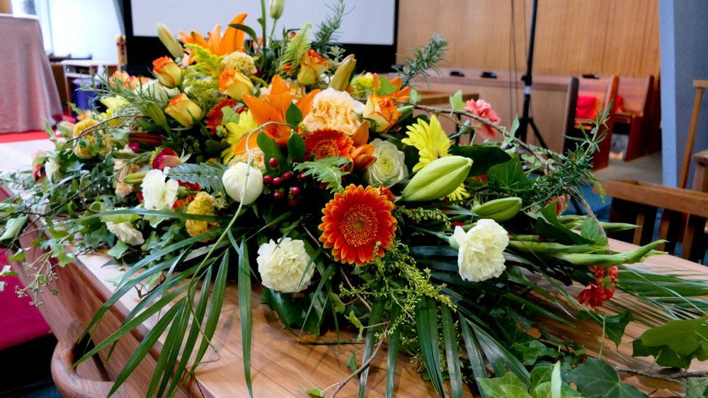 A Coffin Is Decorated with Flowers and Leaves in A Church — Pick-A-Bunch Florists & Gifts In Koumala, QLD