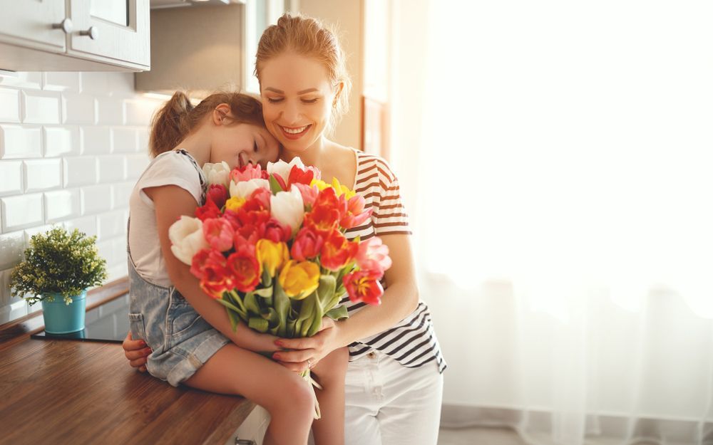 A Little Girl Is Giving an Older Woman a Gift and Flowers — Pick-A-Bunch Florists & Gifts In Alligator Creek, QLD