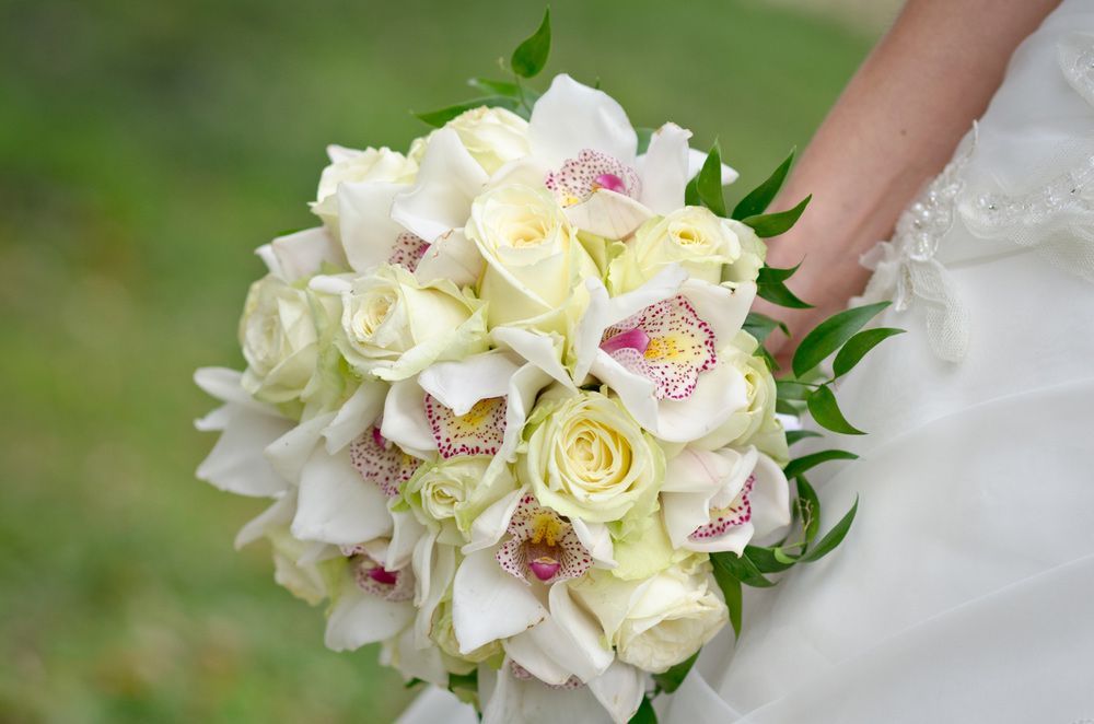 A Bride Is Holding a Bouquet of White Flowers in Her Hand — Pick-A-Bunch Florists & Gifts In Armstrong Beach, QLD