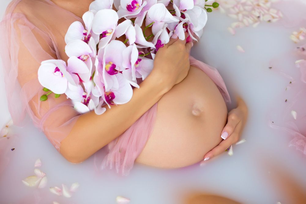 A Pregnant Woman Is Laying in A Bathtub Holding Flowers — Pick-A-Bunch Florists & Gifts In Alligator Creek, QLD