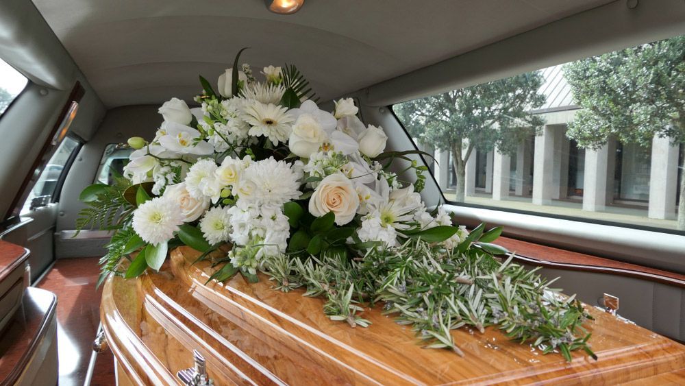 A Coffin Is Sitting in The Back of A Limousine with White Flowers — Pick-A-Bunch Florists & Gifts In Koumala, QLD