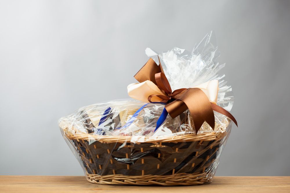 A Gift Basket with A Bow Is Sitting on A Wooden Table — Pick-A-Bunch Florists & Gifts In Sarina, QLD