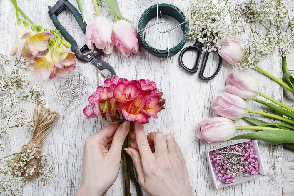 A Woman Is Making a Bouquet of Flowers on A Wooden Table — Pick-A-Bunch Florists & Gifts In Alligator Creek, QLD