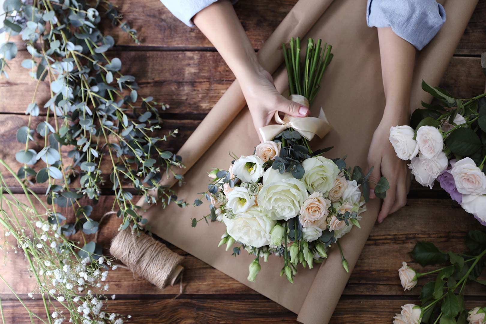 A Person Is Wrapping a Bouquet of Flowers in Brown Paper — Pick-A-Bunch Florists & Gifts In Armstrong Beach, QLD