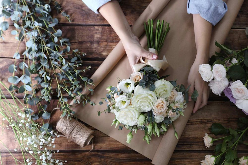 A Person Is Wrapping a Bouquet of Flowers in Brown Paper — Pick-A-Bunch Florists & Gifts In Armstrong Beach, QLD