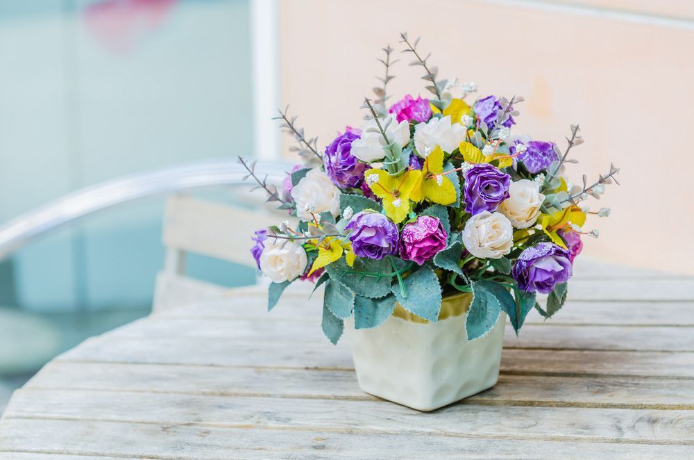 A Vase Filled with Purple and Yellow Flowers Is Sitting on A Wooden Table — Pick-A-Bunch Florists & Gifts In Sarina, QLD