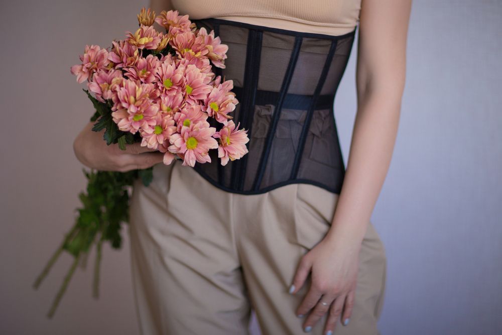 A Woman in A Corset Is Holding a Bouquet of Pink Flowers — Pick-A-Bunch Florists & Gifts In Koumala, QLD