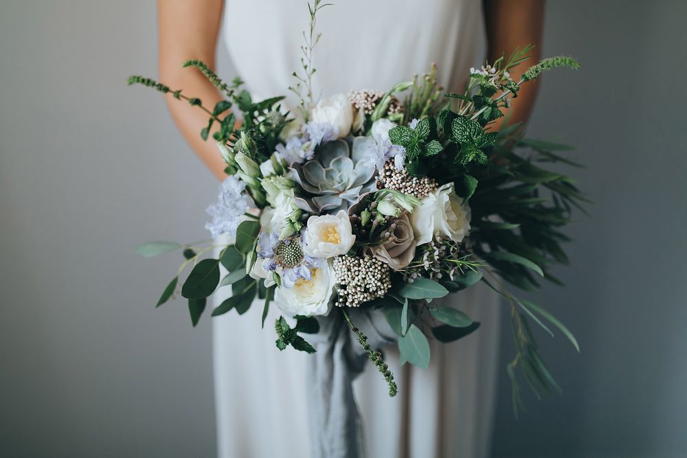 A Woman in A Grey Dress Is Holding a Bouquet of Flowers — Pick-A-Bunch Florists & Gifts In Sarina, QLD