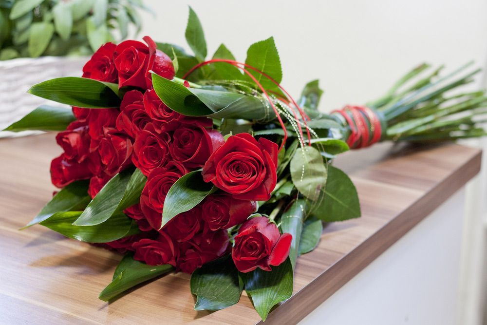 A Bouquet of Red Roses Is Sitting on A Wooden Table — Pick-A-Bunch Florists & Gifts In Koumala, QLD