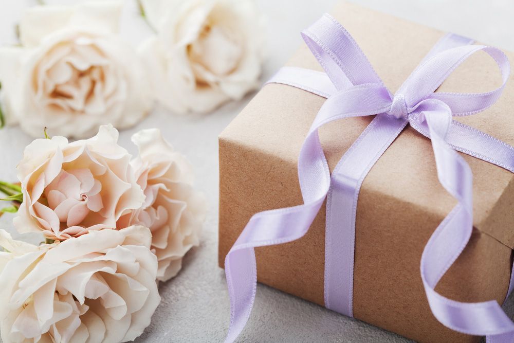A Gift Box with A Purple Ribbon and Roses in The Background — Pick-A-Bunch Florists & Gifts In Hay Point, QLD