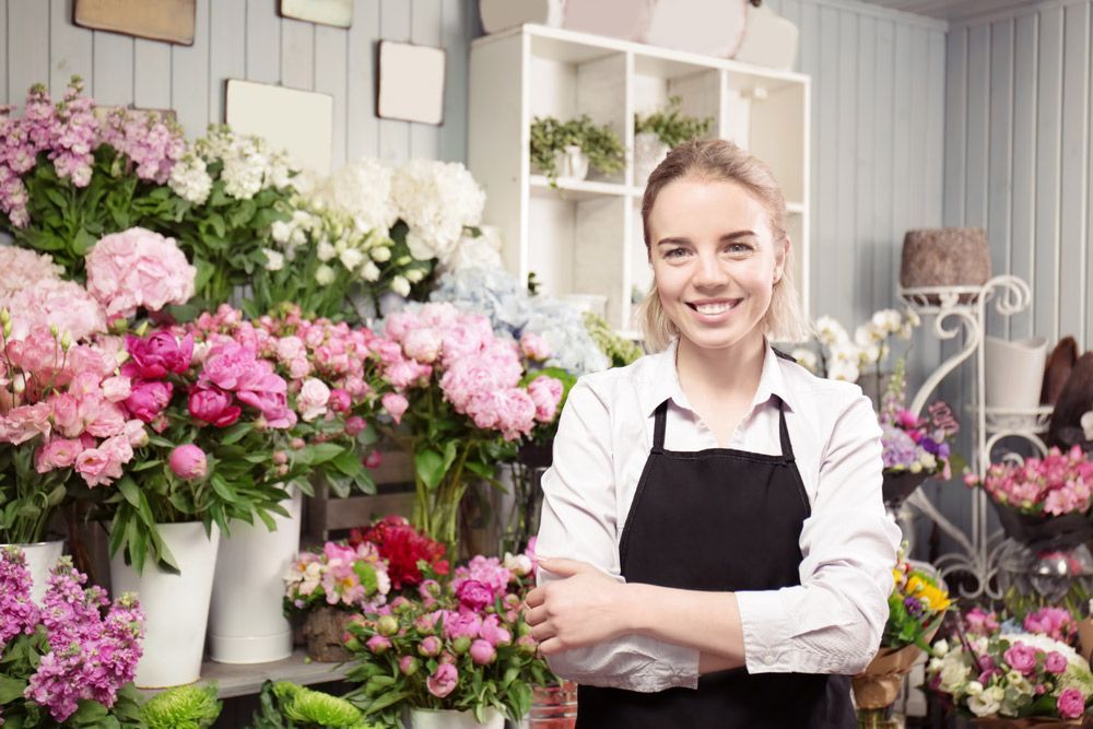 A Woman Is Standing in Front of A Display of Flowers in A Flower Shop — Pick-A-Bunch Florists & Gifts In Alligator Creek, QLD