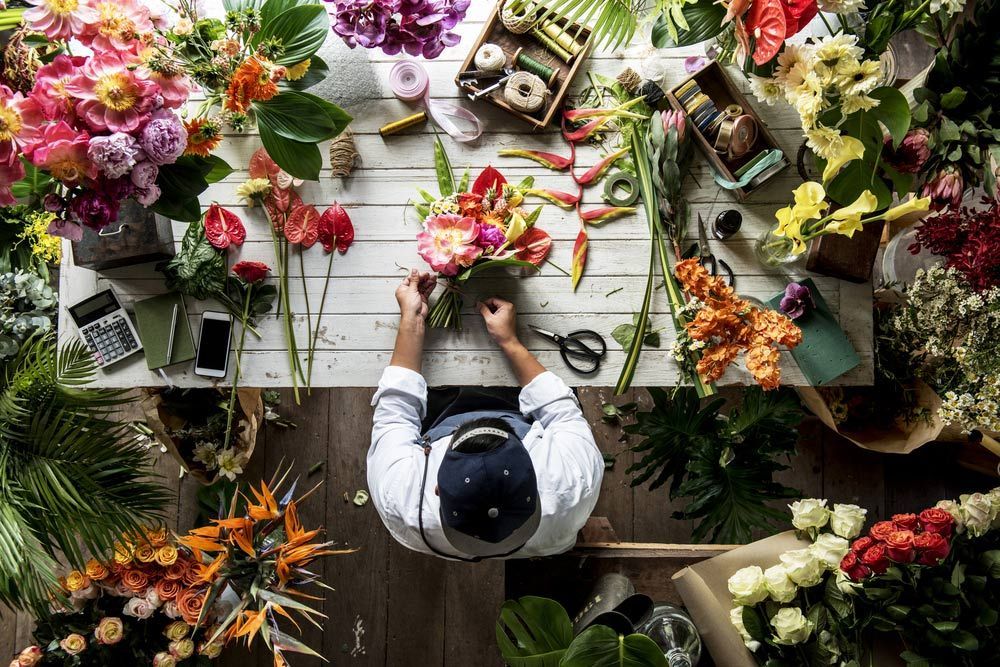 A Man Is Sitting at A Table Surrounded by Flowers — Pick-A-Bunch Florists & Gifts In Hay Point, QLD