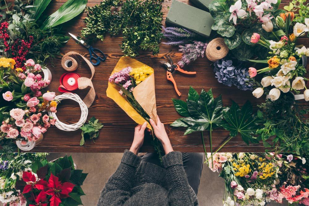 A Person Is Wrapping a Bouquet of Flowers in A Yellow Envelope — Pick-A-Bunch Florists & Gifts In Alligator Creek, QLD